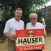 Hauser Contractors and a client in front of sign